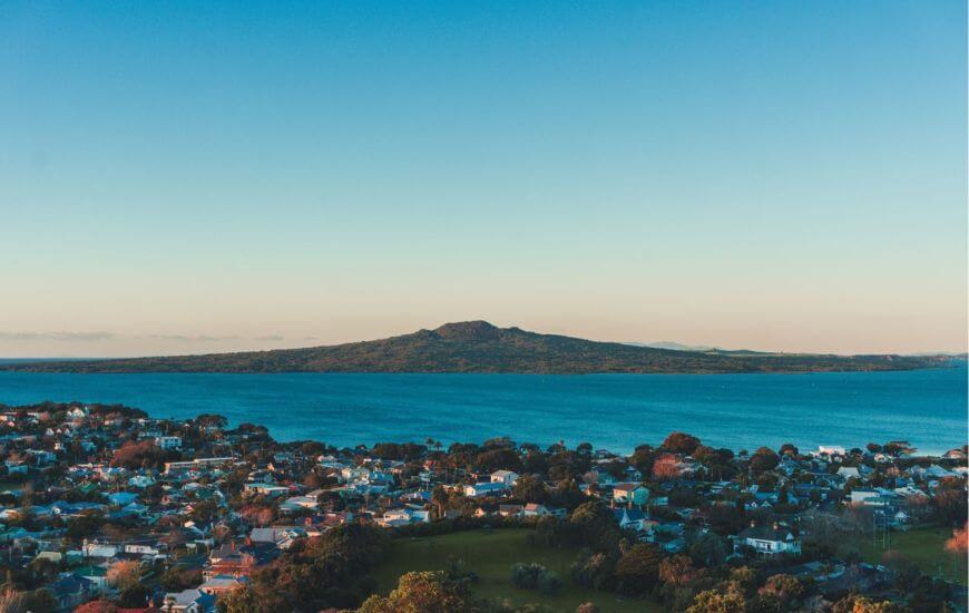 rangitoto island with houses in the foreground which is one of the best day trips from auckland