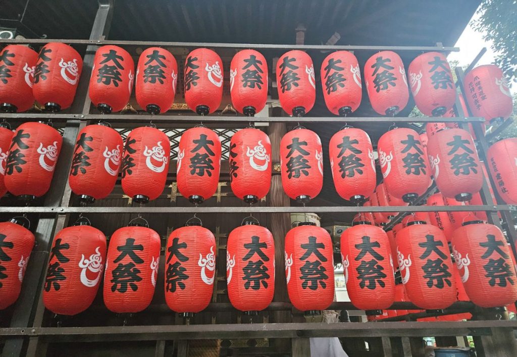 red lanterns displayed along an outdoor wall at a fox shrine in tokyo